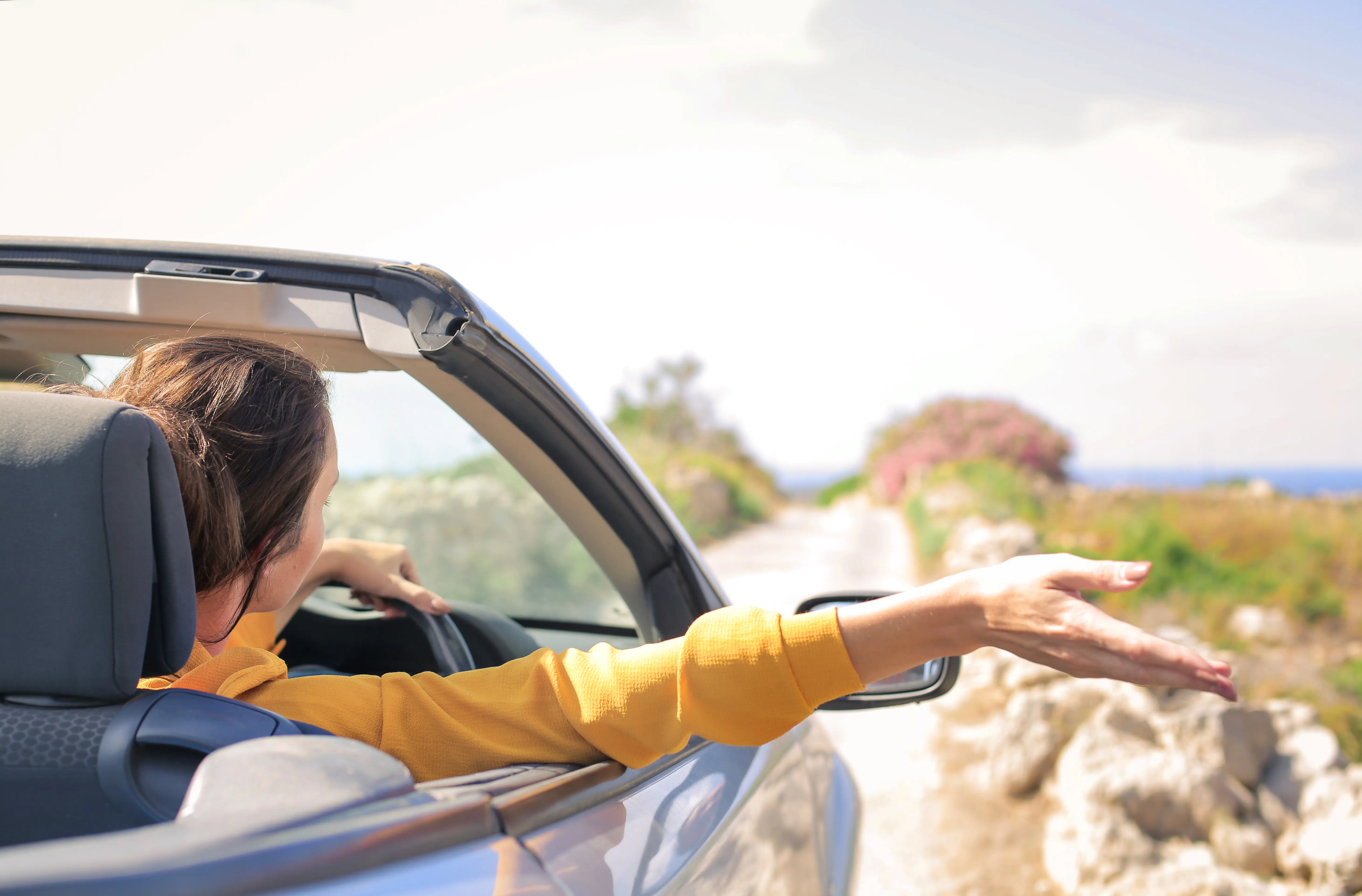 femme dans une voiture décapotable avec un pull jaune