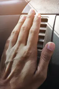 Main devant la climatisation d'une voiture